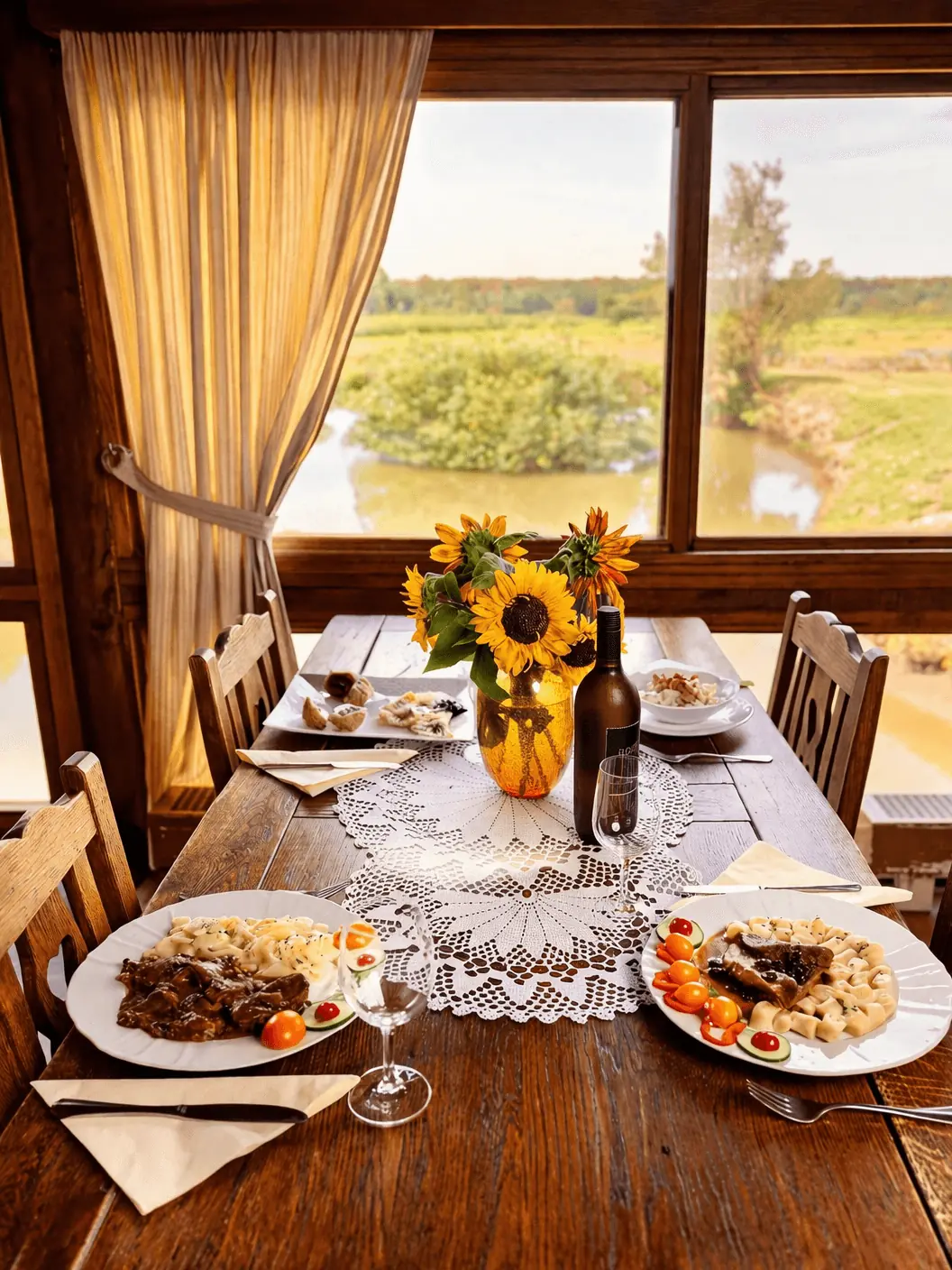 Postavljen stol s jelima i sunčanicama, uz pogled na vodu i zelenilo kroz prozor