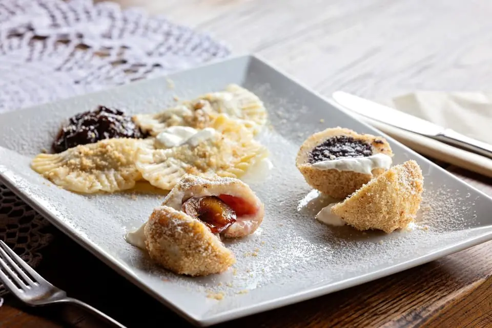 Tačkrle i knedle s pekmezom, makom i kiselim vrhnjem na rustikalnom drvenom stolu